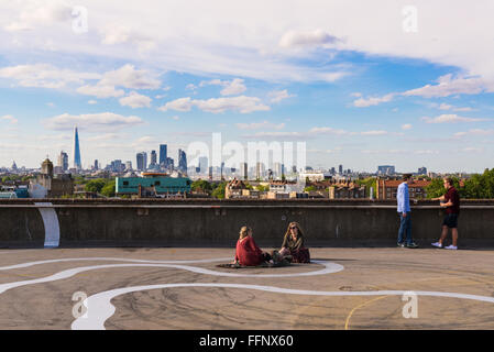 Two girls and two guys drinking beer on the floor of Franks Cafe rooftop bar café in Peckham, a cool area in south-east London Stock Photo