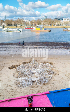 Mountain sand sculpture on the south bank of the Embankment and the River Thames at low tide, London, made for tips Stock Photo