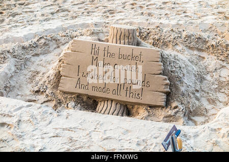 Sand sculpture on the Embankment, River Thames at low tide, London, inscribed 'Hit the bucket, Make a wish, I wished for pounds, And made all this!' Stock Photo