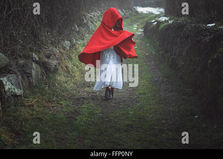 Surreal  portrait of a red hooded woman on a dark country trail Stock Photo
