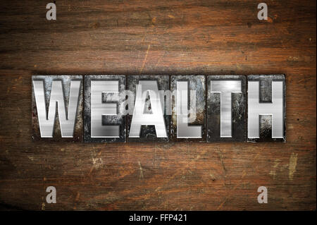 The word "Wealth" written in vintage metal letterpress type on an aged wooden background. Stock Photo