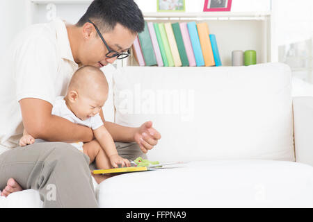 Asian family lifestyle at home. Father and child reading story book on sofa. Stock Photo