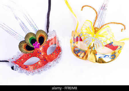 Two masks placed on white, one red and the other golden Stock Photo
