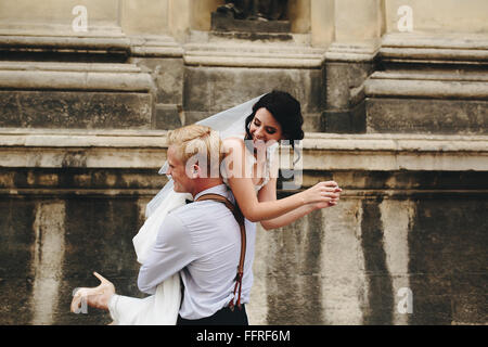 groom carries bride in his arms Stock Photo