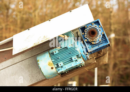 An electric motor at the end of a conveyor belt. A gearbox is attached to the motor. Stock Photo