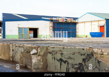 Kallinge, Sweden - February 07, 2016: Scaffoldings stand against an industrial building with packets of insulation on top. Build Stock Photo