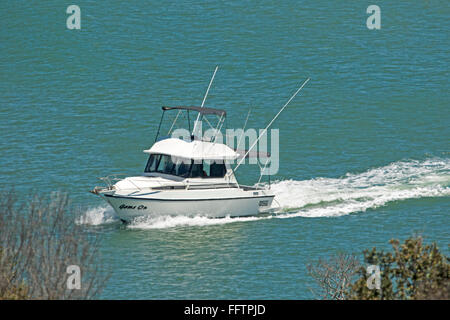 White boat, recreational cabin cruiser speeding across  turquoise blue waters of ocean with white bow wave Stock Photo