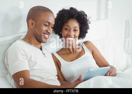Happy couple on bed using tablet Stock Photo