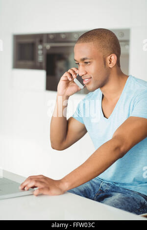 Smiling man calling and using laptop Stock Photo