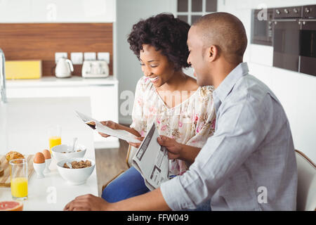 Smiling couple reading magazine and documents during breakfast Stock Photo