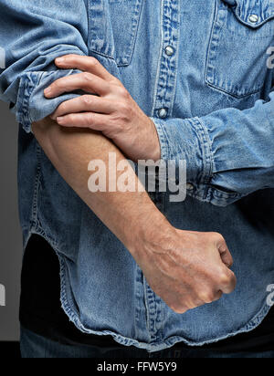 Man in denim shirt rolling up his sleeves Stock Photo