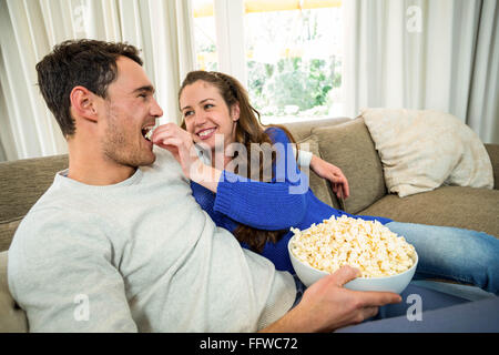 Young couple eating popcorn on sofa Stock Photo