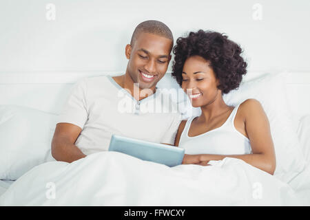 Happy couple on bed using tablet Stock Photo