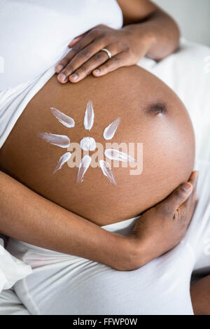 Pregnant woman applying cream on her belly Stock Photo