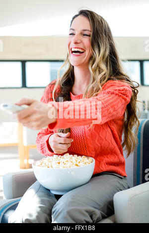 smiling woman eating popcorn and watching tv Stock Photo