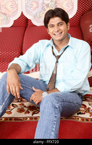 young man sitting on Sofa  relaxing and smiling  MR # 687C Stock Photo