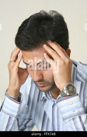 young man touching his head with both hands and thinking MR # 687 I Stock Photo