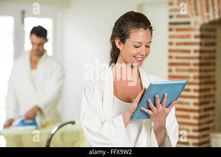 Beautiful woman in bathrobe using digital tablet Stock Photo