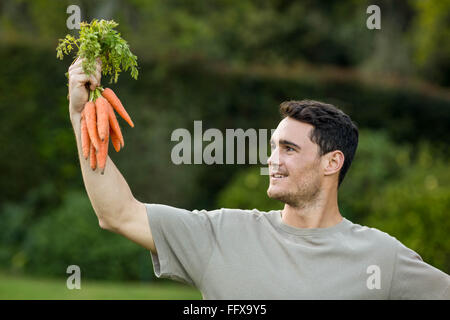 Young man holding bunch of carrots Stock Photo