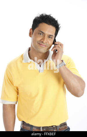 Confident young man holding mobile phone to his left ear and talking MR#703R Stock Photo