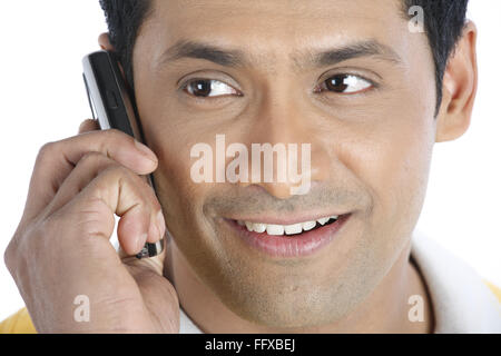 Confident young man holding mobile phone to his right ear and talking MR#703R Stock Photo