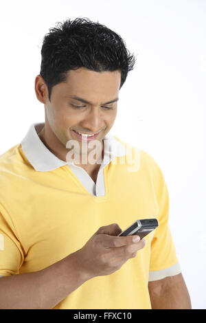 Confident young man looking at mobile phone holding in right hand and dialling number MR#703R Stock Photo