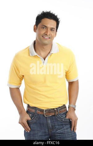 Confident young man just standing kept thumbs in his jeans pant pockets wearing yellow t shirt MR#703R Stock Photo