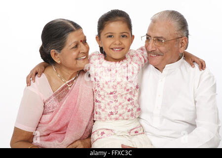 Granddaughter sitting between grandparent kept hand on their shoulders MR#703O,703P,703Q Stock Photo