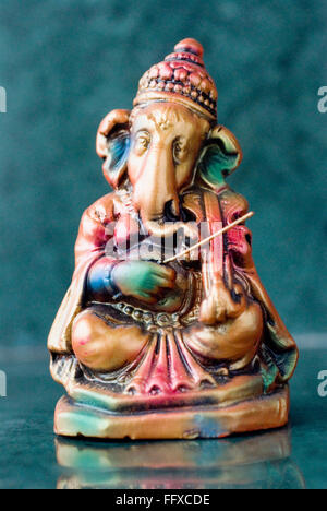 Lord Ganesha ganpati plaster Idol sitting colourful playing violin musical string Instrument Stock Photo