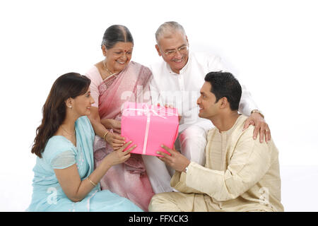 Young woman and man sitting down holding gift box and giving to old parent MR#703P,703Q,703R,703S Stock Photo