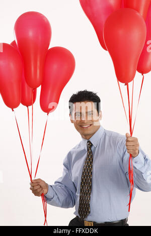 Businessman holding red color gas balloons in both hands MR#703T Stock Photo