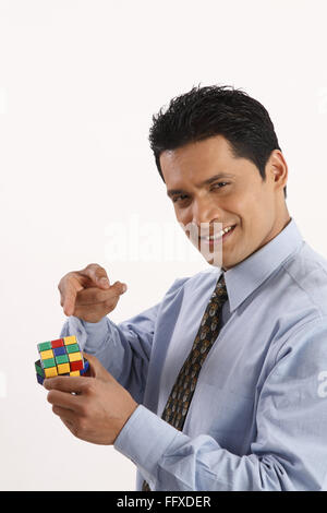 Businessman holding Rubik cube in one hand and pointing index finger MR#703T Stock Photo
