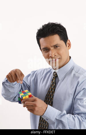 Businessman holding Rubik cube in one hand and pointing index finger MR#703T Stock Photo