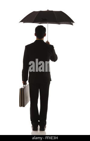 Businessman holding black opened umbrella on head with briefcase in other hand MR#703T Stock Photo