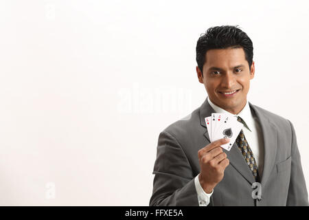 Businessman holding four aces of playing cards in his thumb and index finger of right hand MR#703T Stock Photo