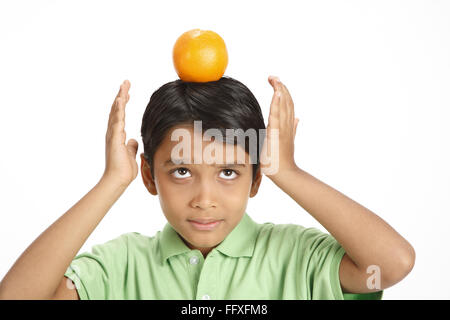 Ten year old boy kept orange on head and trying to balance it MR#703V Stock Photo