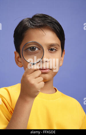 Ten year old boy looking through magnifying glass and both eyes open MR#703V Stock Photo