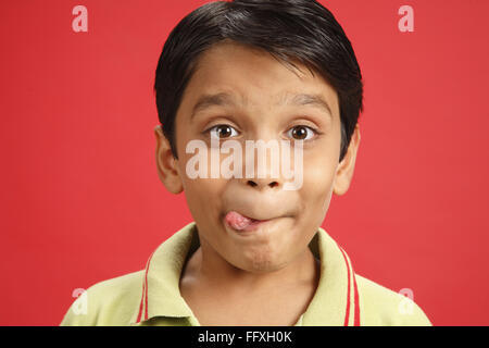 Ten year old boy taking out his tongue from right side indicating good test MR#703V Stock Photo