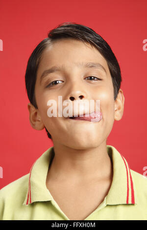 Ten year old boy taking out his tongue from right side indicating good test MR#703V Stock Photo