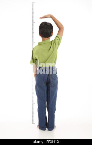 Ten year old boy standing near height scale and checking MR# 703V Stock Photo