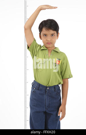 Ten year old boy holding his hand above his head to check his height MR#703V Stock Photo