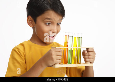 Ten year old boy holding test tubes filled with color water MR#703V Stock Photo