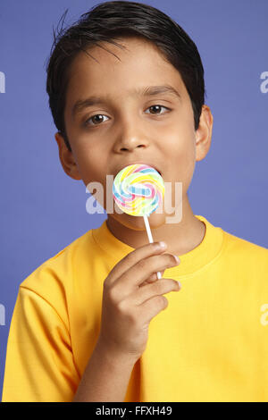 Ten year old boy holding large colourful lollipop licking MR#703V Stock Photo