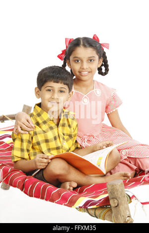Ten and eight years old girl and boy sitting on charpoy MR#743C,743D Stock Photo