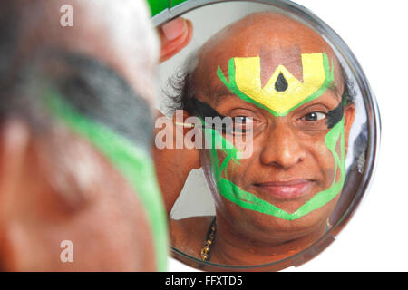 South Indian kathakali dancer applying makeup looking in mirror ; Kerala ; India MR#761C Stock Photo