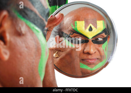 South Indian kathakali dancer applying makeup looking in mirror ; Kerala ; India MR#761C Stock Photo