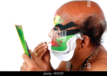 South Indian kathakali dancer applying makeup looking in mirror ; Kerala ; India MR#761C Stock Photo