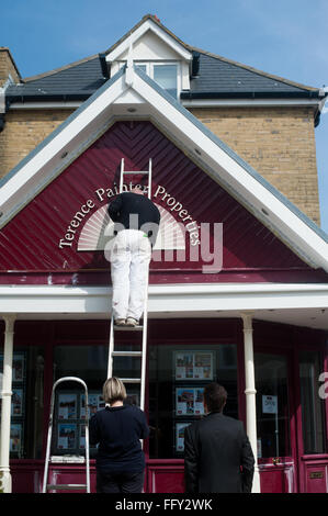 Man painting front of estate agent on ladder in Broadstairs, Kent,UK Stock Photo