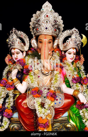 Richly decorated idol lord ganesh elephant headed god sitting consorts Riddhi Siddhi Ganpati festival Mandai Pune Maharashtra Stock Photo