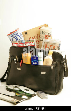 Black leather office bag filled with newspaper magazine beauty product CD and mobile Stock Photo